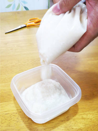 袋の甘酒をタッパー容器に絞り出す。